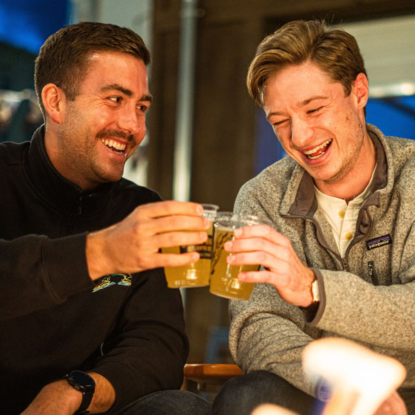 two people smiling and holding beer making a cheers
